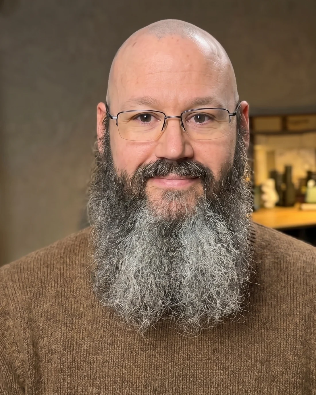 Scott Somers, bearded and bespectacled, in a brown sweater in front of a bookshelf